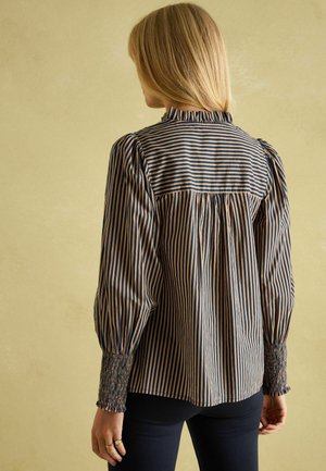 Gestreifte Bluse mit elastischen Bündchen, in navy und creme mit vertikalen Streifen. Weicher Stoff mit einem gerafften Rückendesign und Rüschenausschnitt.