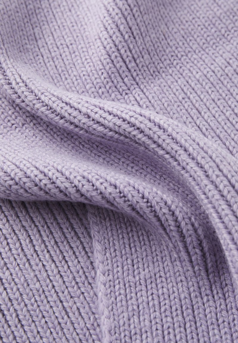Zbliżenie na miękką, prążkowaną lawendową dzianinę z widocznymi teksturowanymi ściegami i delikatnymi fałdami.