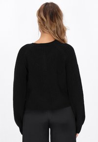 Maglione nero lavorato a maglia con un motivo a diamante testurizzato, maniche ampie e lunghezza cropped. Materiale morbido con dettagli a coste sui polsini e sull'orlo.
