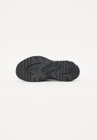 Semelle de chaussure de sport noire avec une surface en caoutchouc texturé, dotée de rainures et d'un logo central. Conçue pour l'adhérence et la durabilité.