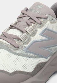 Hellgrauer und lavendelfarbener Laufschuh mit strukturiertem Strickobermaterial, gepolstertem Kragen und reflektierenden Akzenten mit Logo auf der Zunge.