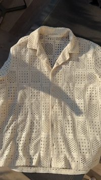 Cream-colored short-sleeve shirt with a textured grid pattern and button closure, made from breathable, knitted fabric.