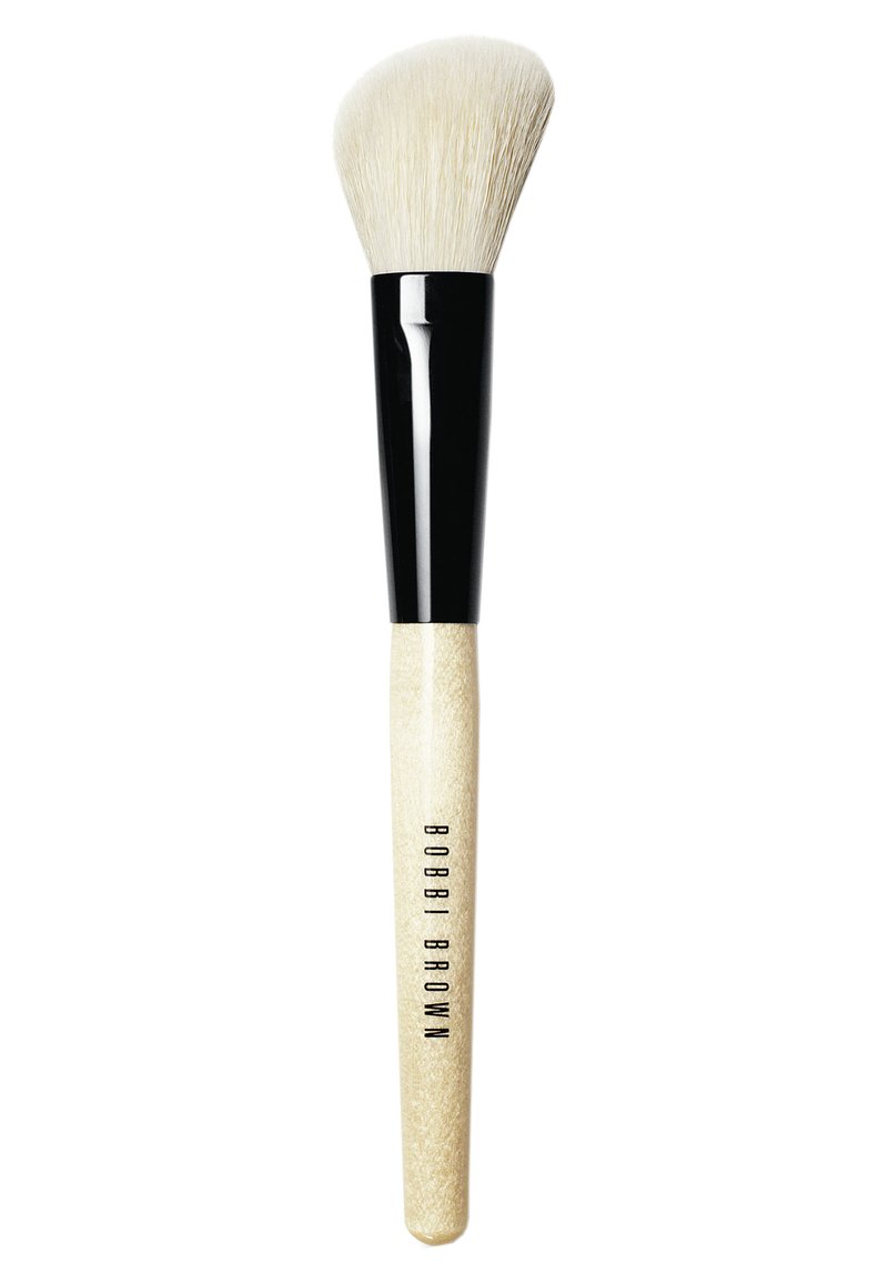 Pinceau de maquillage rond avec des poils blancs doux, une virole noire brillante et un manche en bois clair gravé avec "BOBBI BROWN."