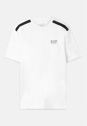 Camiseta blanca de manga corta con rayas negras en los hombros. Presenta un pequeño logo negro en el pecho. Fabricada con una tela suave y lisa.