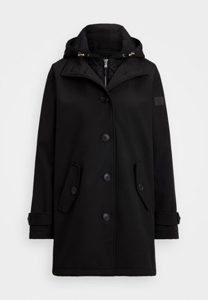 Casaco impermeável preto com capuz, apresentando um fecho de botões duplo, dois bolsos laterais e um emblema na manga.