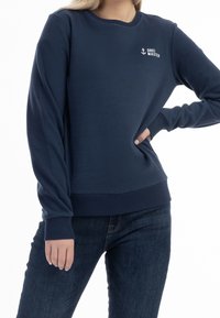 Felpa blu navy in un morbido misto cotone, caratterizzata da un colletto a girocollo e polsini a coste, con un piccolo logo bianco sul petto.