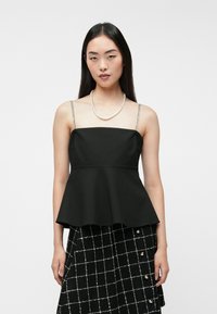 Fekete peplum felső állítható spagetti pántokkal, texturált ezüst díszítéssel. Egyszínű háttér előtt elhelyezve.