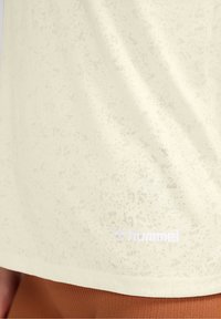 Ljusgul t-shirt med en strukturerad mönster, med "hummel"-logotypen i vitt vid fållen. Mjuk, andningsbar tyg, avslappnad passform.