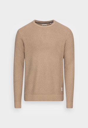 Suéter de punto beige con un patrón texturizado, escote redondo y mangas largas. Puños y dobladillo acanalados con un pequeño detalle de logotipo en la parte inferior.