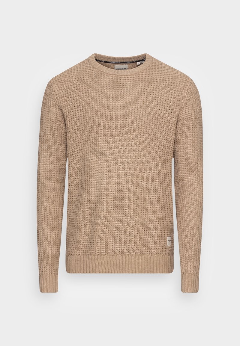 Pull en tricot beige avec un motif texturé, encolure ronde et manches longues. Poignets et ourlet côtelés avec un petit détail logo en bas.