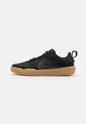 Baskets basses noires avec empeignes en mesh et suède, semelle en caoutchouc naturel, languette au talon et subtil logo Swoosh foncé sur le côté.