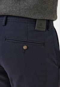 Marineblaue Hosen aus strukturiertem Stoff, mit einer Gesäßtasche mit Knopfverschluss und einem schwarzen Lederetikett mit "redpoint"-Logo.