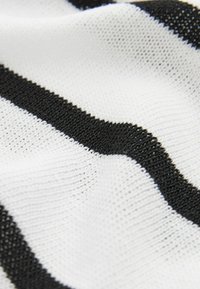 Knit fabric with alternating black and white stripes, showcasing a textured, woven surface with a soft appearance. Ideal for casual wear.