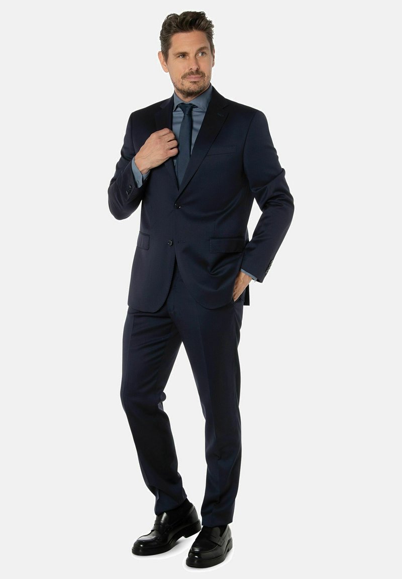Marineblauwe pak met een getailleerde pasvorm, enkel-breasted jasje, notch revers, en rechte broek. Gekocht met een lichtblauw overhemd en zwarte schoenen.