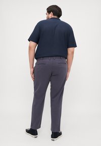 Navy stripe short-sleeve polo shirt, gray trousers, and black sneakers; visible back pockets and a relaxed fit. Smooth texture overall.