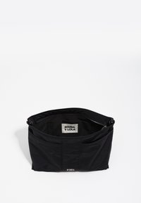 Borsa tote nera in nylon con una superficie testurizzata, zip sulla parte superiore e etichetta interna visibile. Presenta delle pieghe per un tocco di dimensione in più.