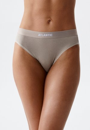Kobieta nosząca beżową bieliznę w stylu bikini z nadrukiem "ATLANTIC" na pasku, na jednolitym tle.