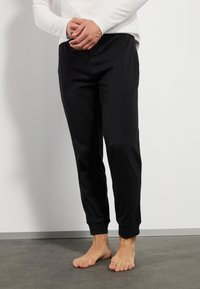 Black tapered joggers made of soft fabric, featuring ribbed cuffs and an elastic waistband. Smooth texture with a streamlined design.