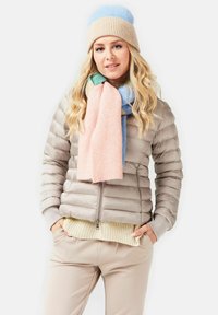 Beige puffer jacket with a zip and ribbed cuffs; layered with a cream knit sweater. Multicolored striped scarf and textured knit beanie.