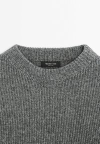 Pull en maille côtelée grise avec col rond, affichant l’étiquette de marque Massimo Dutti à l’intérieur du col.