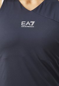 Top deportivo navy de tirantes en una suave tela elástica, con un diseño de escote en V y un logo blanco de EA7 Emporio Armani en la parte frontal.