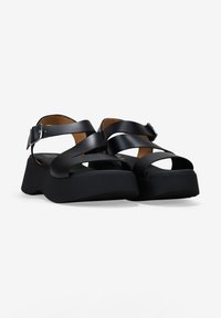 Sandalias de plataforma negras con diseño de tiras entrelazadas, acabado suave, hebilla ajustable en el tobillo y plantilla acolchada para mayor comodidad.