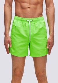 Pantaloni da nuoto verde neon realizzati in materiale leggero, con vita elasticizzata e coulisse regolabile, e una texture liscia.