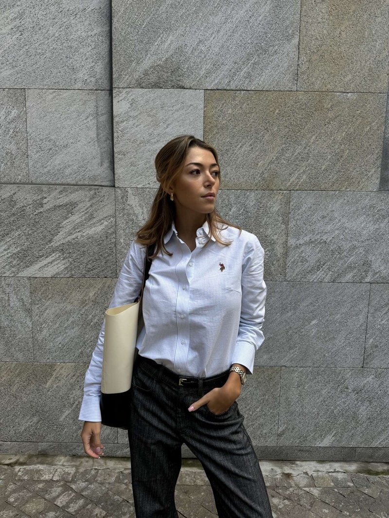 Fehér csíkos gombos ing kis logóval, fekete-fehér csíkos nadrág és kéttónusú táska. Szürke háttér.