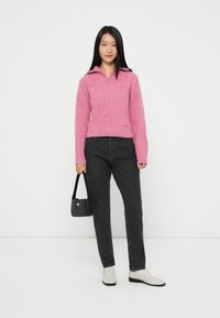 Rosa strikkegenser med krage, med et teksturert mønster. Kombinert med svarte jeans og lysfargede ankelstøvler.