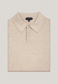 Beżowa koszulka polo wykonana z dzianiny. Posiada klasyczny kołnierzyk, zapięcie na trzy guziki oraz ryflowane wykończenia przy kołnierzyku i u dołu.