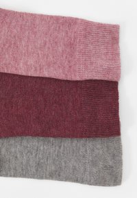 Trzy próbki dzianiny w kolorach różowym, burgundowym i szarym, prezentujące różnorodne faktury i sploty; każda próbka jest ułożona poziomo.