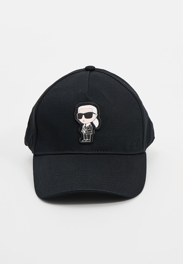 Gorra de béisbol negra con una pequeña figura de dibujos animados que lleva gafas de sol, cabello blanco y un traje bordada en el centro frontal.