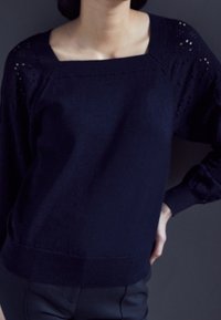 Mörkblå stickad tröja med fyrkantig halsringning, texturerade detaljer på ärmarna och ribbat avslut. Mjuk tyg med en slät yta.