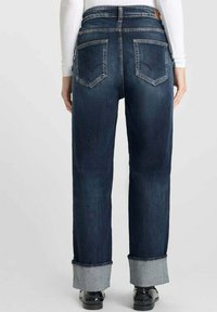 Jean en denim bleu foncé avec une coupe droite, présentant des ourlets roulés, deux poches arrière et une taille mi-haute.