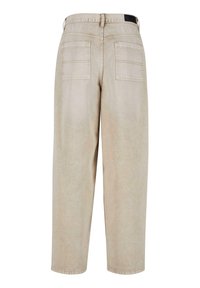 Beige, loose-fitting denim pants with a straight leg, featuring two back pockets and a waistband with a tag detail.