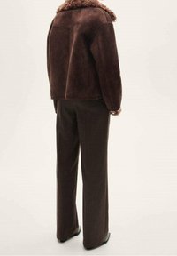 Brown suede jacket with a faux fur collar, paired with dark brown straight-leg trousers, viewed from the back. Smooth texture, no visible patterns.