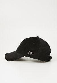 Casquette de baseball en velours côtelé noir avec une visière courbée, une sangle arrière réglable et un logo brodé blanc sur les panneaux avant et latéraux.