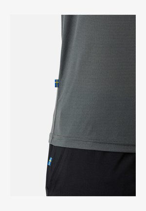 Grijs getextureerd shirt en zwarte broek hebben beide kleine Zweedse vlaglabeltjes bij de zoom en de zakken.