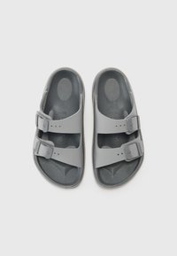 Grå sandaler med to justerbare stropper, laget av teksturert gummilignende materiale, med flat såle og hevet innersåle for komfort.