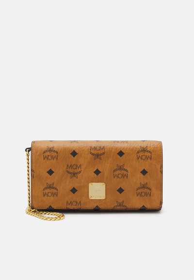 Portefeuille en cuir marron avec un motif de logos MCM noirs, un logo en plaque dorée, et une lanière en chaîne pour plus de polyvalence.