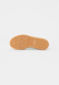 Suela de zapato de goma con un patrón de agarre texturizado, que presenta un diseño circular y un color marrón claro. La parte inferior tiene un patrón triangular para mayor tracción.