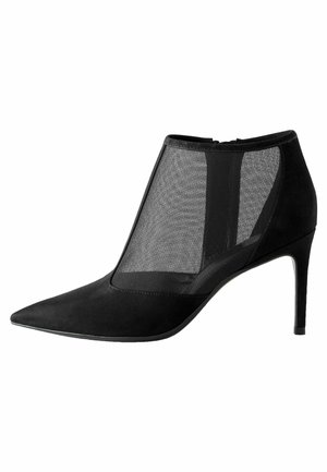 Bottine noire à talon haut avec bout pointu et panneaux en mesh transparent sur les côtés, dotée d'un talon stiletto fin.