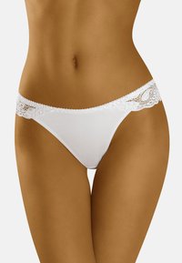 Weiße Tanga-Unterwäsche mit einem glatten Mittelteil und dekorativem Spitzenbesatz an der Taille, der komplizierte Muster entlang der Kanten aufweist.