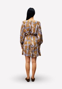 Braun gemustertes Kleid mit langen Ärmeln und einem Gürtel, das floral und abstrakte Designs in Blau und Creme aufweist. Weicher Stoff, knielang.