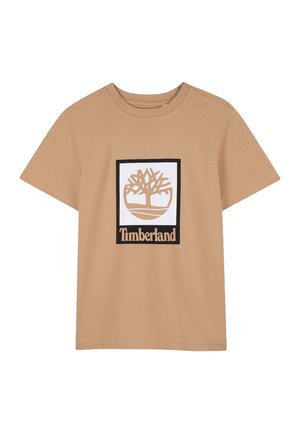 T-shirt à manches courtes couleur sable avec un col rond, arborant au centre un carré blanc contenant un logo d'arbre stylisé et le texte "Timberland" en dessous.