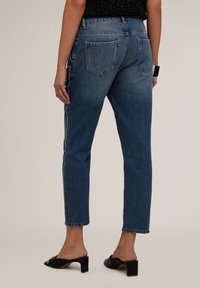 Hoge taille blauwe denim jeans met een rechte pasvorm, met subtiele details in de zijnaad en een vervaagde was. Achterzakken zijn zichtbaar.