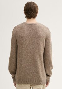 Bruine gebreide trui met een relaxte pasvorm, geribde manchetten en zoom, met een gemêleerde afwerking en verlaagde schoudernaad. Minimalistisch ontwerp.