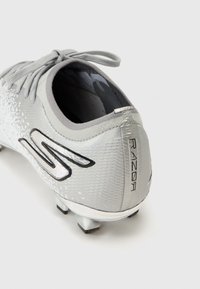 Crampon de football gris avec une tige texturée, présentant un logo et des accents noirs brillants, ainsi que des pointes argentées pour la traction sur la semelle.