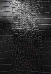 Cuir noir avec embossage en crocodile et finition brillante. Présente un motif texturé d'écailles, offrant profondeur et intérêt visuel.