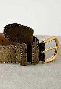 Cintura in suede marrone con fibbia in metallo dorato, dettagli doppi cuciti e retro in pelle liscia, che mostra una superficie testurizzata.